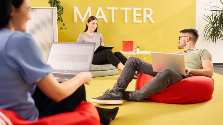3 Mitarbeiter auf modernen Sitzsäcken im Loungebereich der IT sitzend. Alle haben einen Laptop auf den Knien.