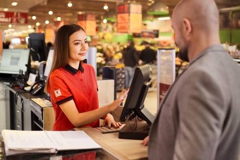 Kaufland-Verkaufsmitarbeiterin im Gespräch mit einem Kunden an der Informationstheke.